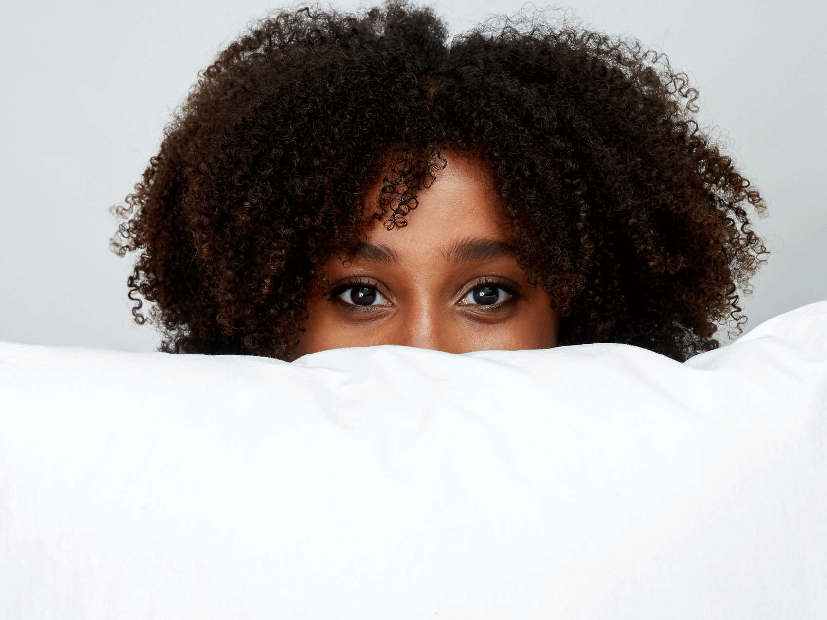 woman peeking behind pillow